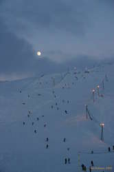 Lots of people enjoying some snow under a fresh moon
