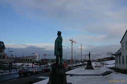 Some yellow spindly statues stand with some old bronze ones